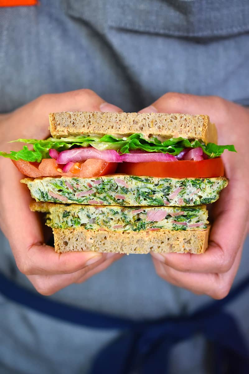 Two hands are holding a St. Paul sandwich, two egg foo young patties in between two slices of paleo and gluten-free bread.