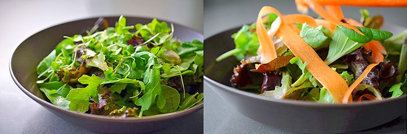 A brown shallow bowl is filled with salad greens and carrot ribbons.