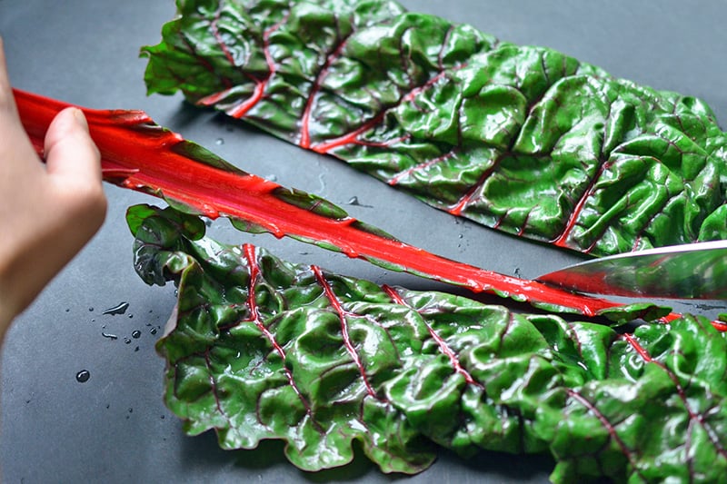 Cutting out the stems of rainbow swiss chard with a knife.