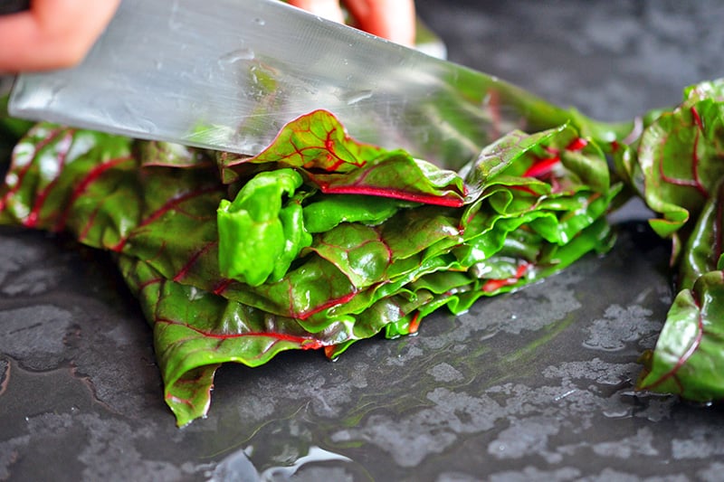 Chopping the leaves of swiss chard for a swiss chard salad.