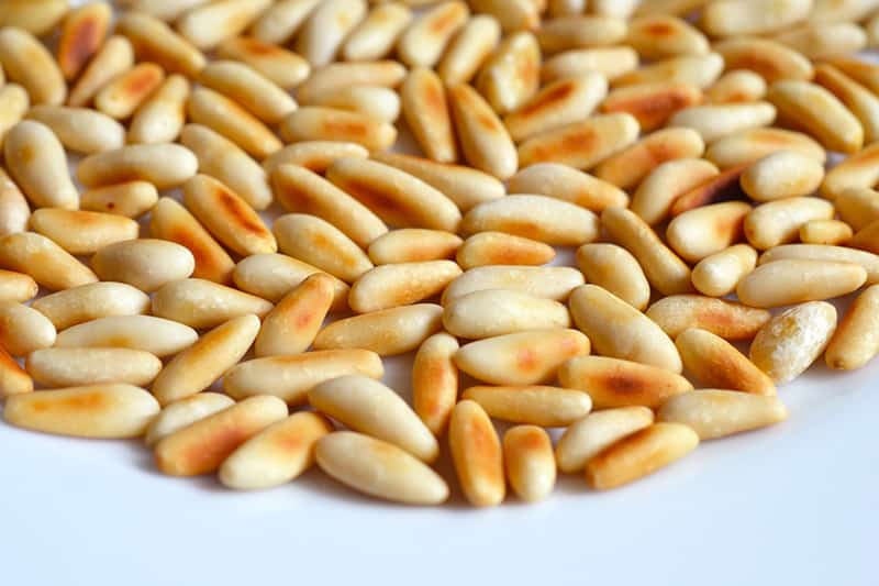 Toasted pine nuts on a plate for a swiss chard salad.