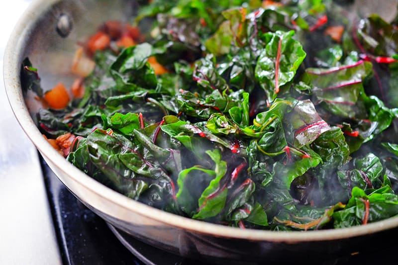 Swiss chard leaves in a pan getting cooked down.