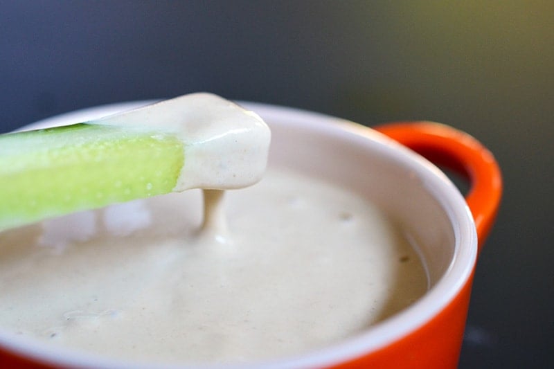 A slice of cucumber is dipped in a bowl of Tonnato Sauce 
