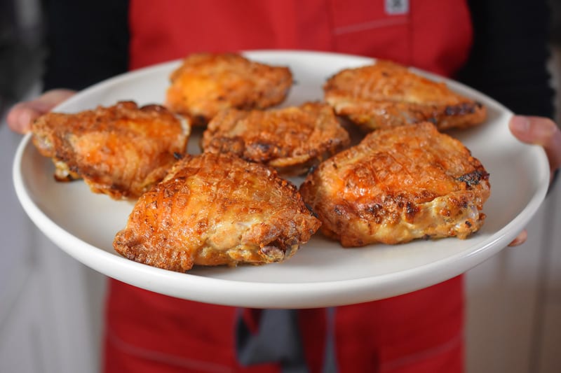 A person is holding up a plate of Umami Roast Chicken 
