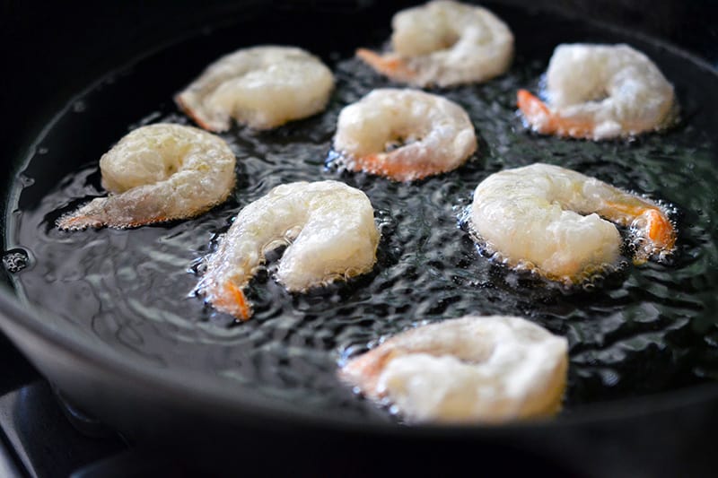 Frying the shrimp in a cast iron skillet to make Paleo Walnut Shrimp 