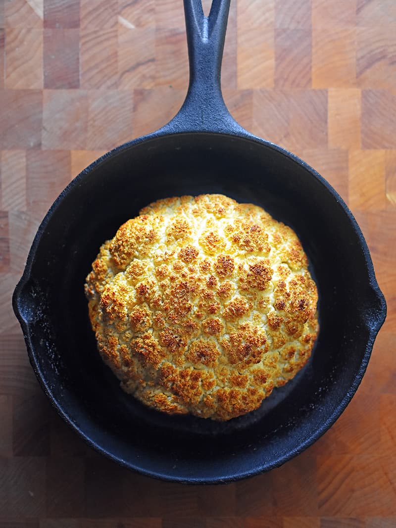 An overhead shot of Whole Roasted Cauliflower in a cast iron skillet.