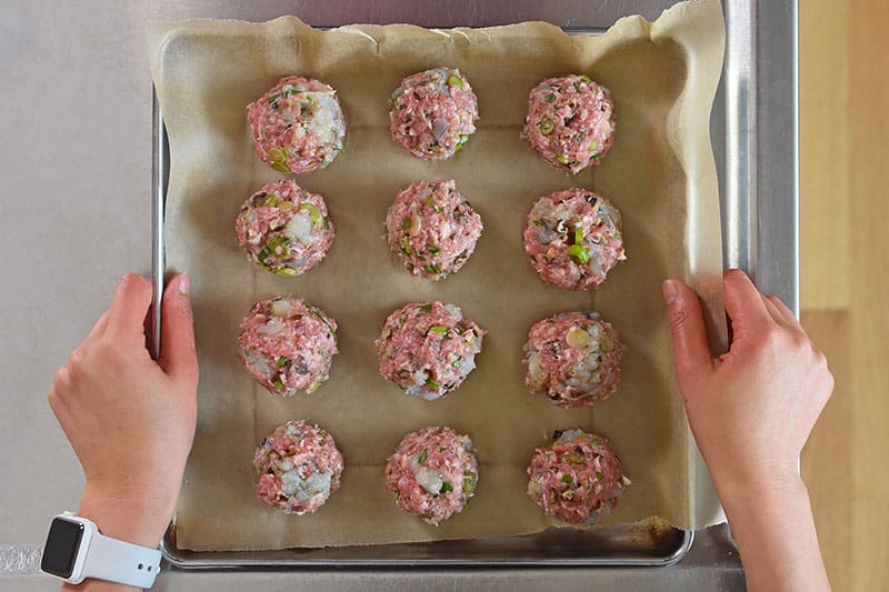An overhead shot of Wonton Meatballs on a parchment lined rimmed baking sheet