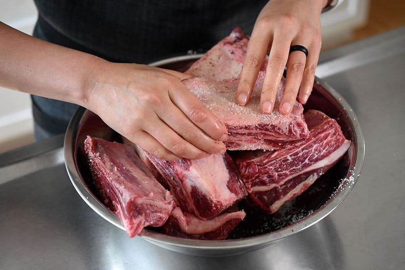 Rubbing the salt evenly over the short ribs.