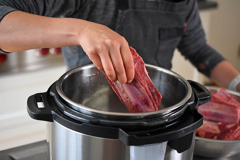 Placing the salted short ribs into the Instant Pot