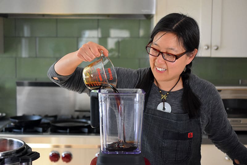Pouring coconut aminos into a blender to make the marinade.
