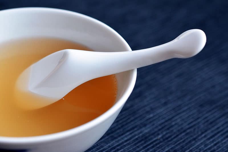 Bowl of chicken bone broth with a spoon.