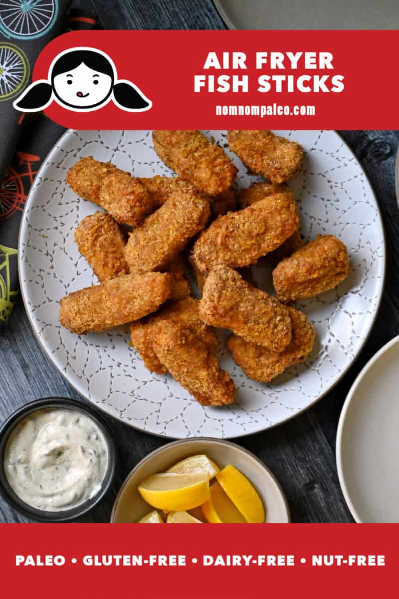 An overhead shot of a plate of air fryer fish sticks next to a bowl of tartar sauce and lemon slices.