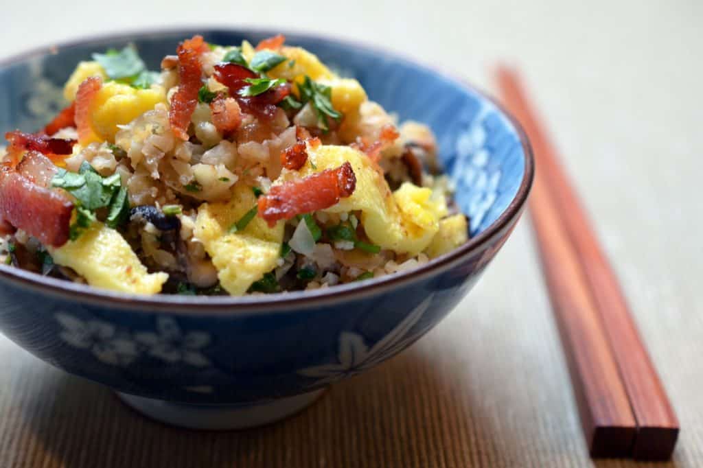 A side shot of Asian Cauliflower Fried Rice in a blue bowl with a pair of chopsticks on the right
