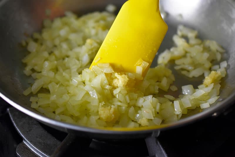 Sautéed onions and minced garlic frying in a pan.