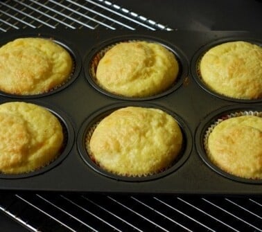 Six cheesy muffins in a muffin tin.