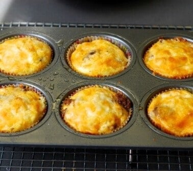 A tray of six mini frittata muffins with cheese and bacon.