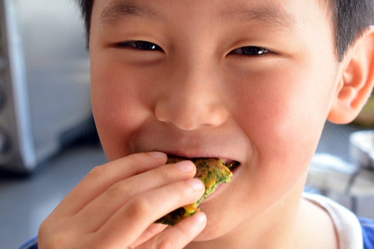 A cute Asian boy is happily eating a paleo Egg Foo Young.