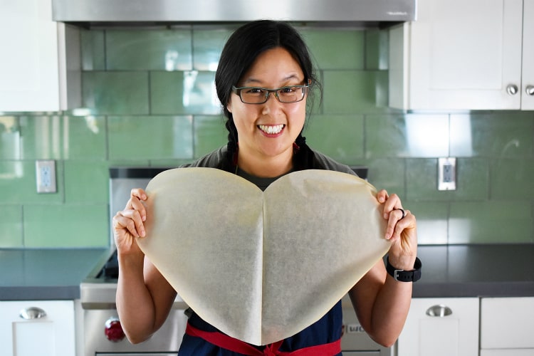 Holding up a heart shaped parchment paper to make Fiona’s Phenomenal Fish Packets 