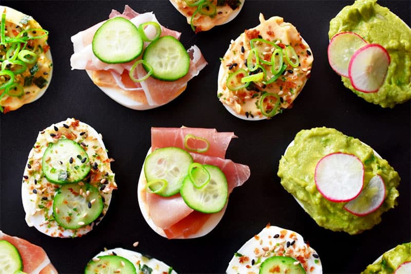 An overhead shot of a variety of Lazy Devils topped with different toppings.