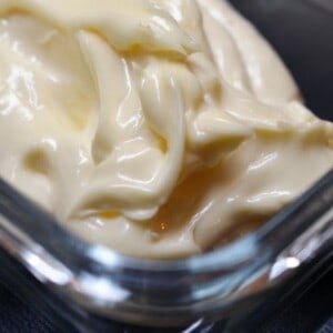 A closeup of thick and creamy paleo mayonnaise in a glass container.