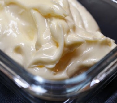 A closeup of thick and creamy paleo mayonnaise in a glass container.
