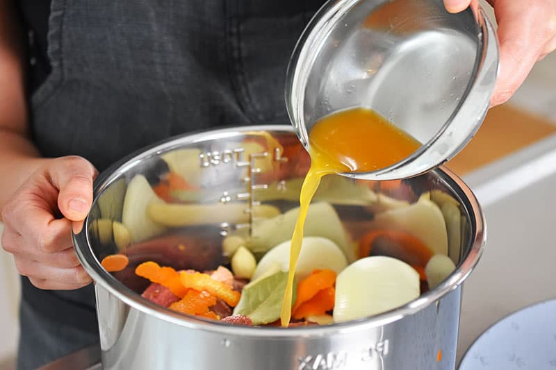Pouring the the orange juice into the Instant Pot for the carnitas recipe.