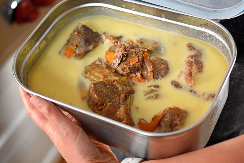 A stainless steel container of Instant Pot (Pressure Cooker) Carnitas from the refrigerator with hardened fat on top