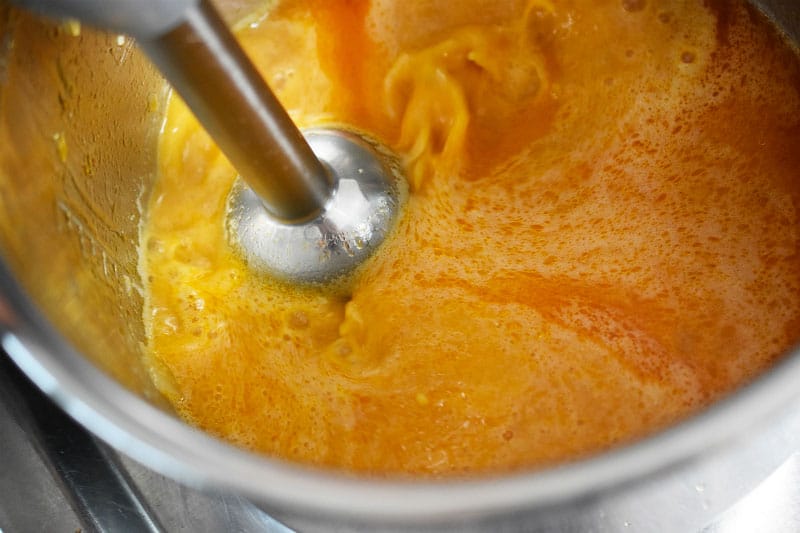 An immersion blender is pureeing gravy in an Instant Pot metal insert.