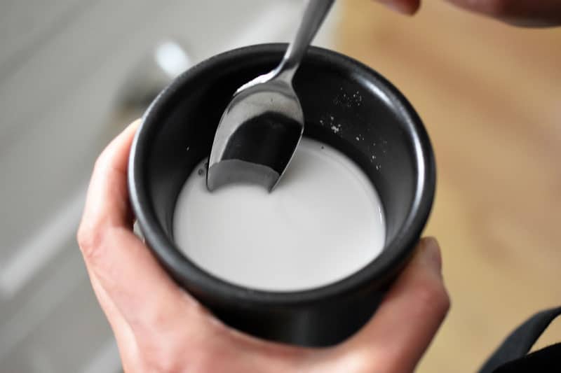 An overhead shot of a black ramekin filled with an arrowroot slurry.