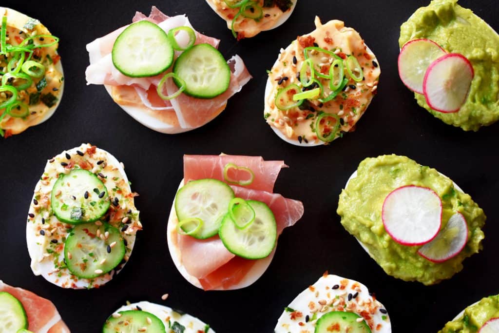 An overhead shot of hard boiled eggs covered with lots of different toppings.