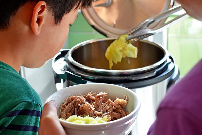 Using tongs to grab cooked cabbage out of an instant pot.