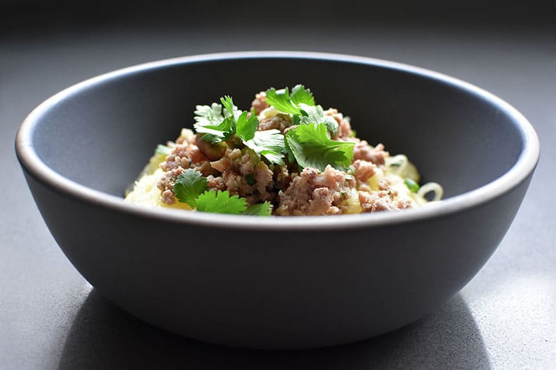 A side view of a bowl of Instant Pot (Pressure Cooker) Spaghetti Squash topped with ground pork stir fry and cilantro