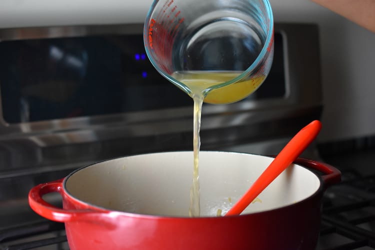 Pouring broth into the pot of Pork and Napa Cabbage Soup 