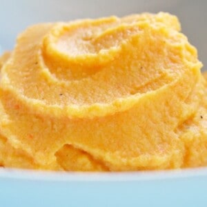 A bowl containing a puree of cauliflower and carrot.