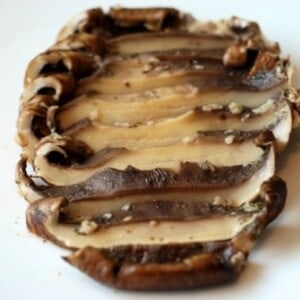 A white plate with sliced Roasted Portobello Mushroom with Lemon and Garlic