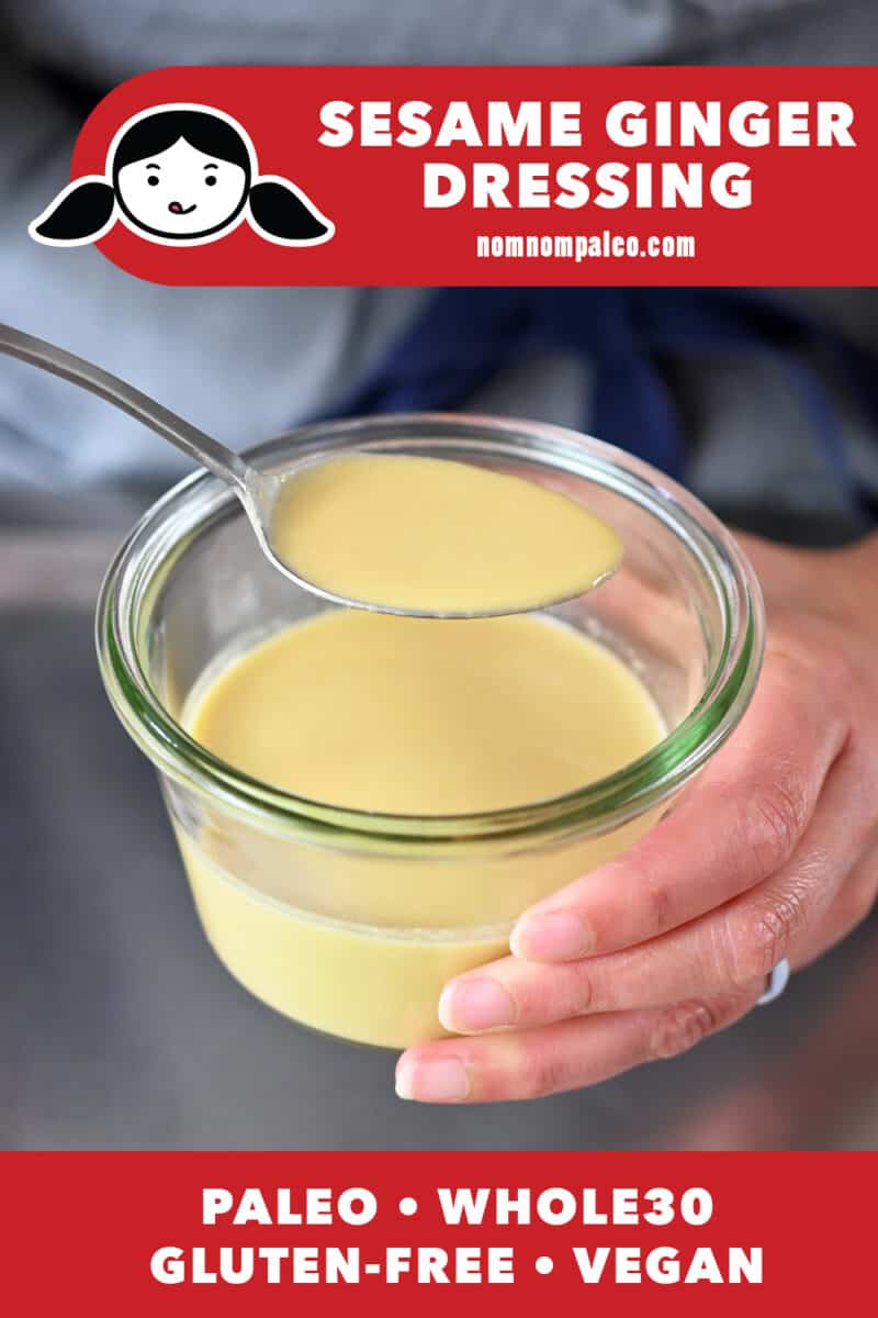 A spoon is lifting up a spoonful of sesame ginger dressing from a clear jar.