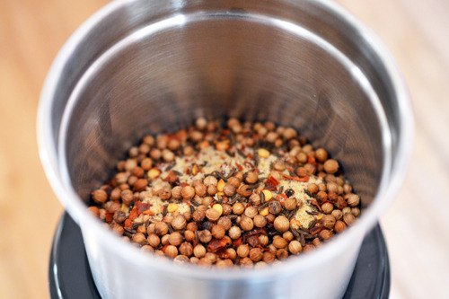 The toasted spices and ingredients for tabil seasoning blend in a spice grinder.