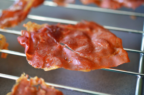 A baked and crispy piece of prosciutto on a wire rack.