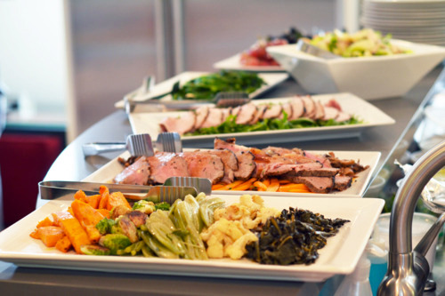 Platters of food lined up on a kitchen countertop.