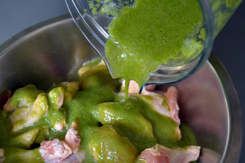 Adding the marinade to a bowl of chicken wings for chili lime chicken.