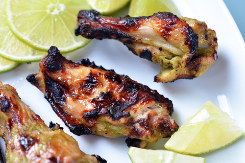 Chili lime chicken wings on a plate with sliced up lime.