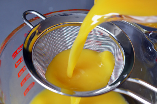 Straining the egg and bone broth mixture for paleo chawanmushi through a fine mesh sieve.