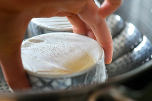 Someone placing the cups into the steamer insert.