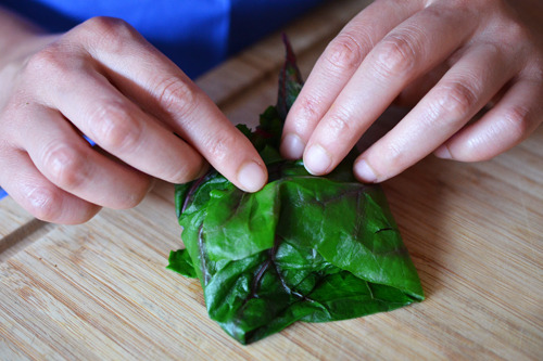 Wrapping the lamb mixture for lamb dosas in swiss chard leaves.