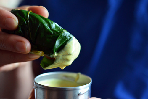 Someone dipping a lamb dosa into the coconut crème.