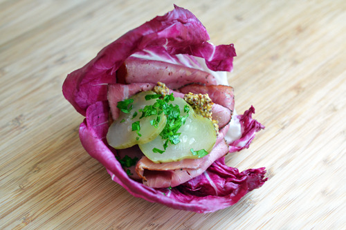 A radicchio wrap with pickles and prosciutto.