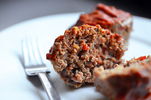 Meatloaf muffins on a plate, with one sliced open to reveal the inside texture.