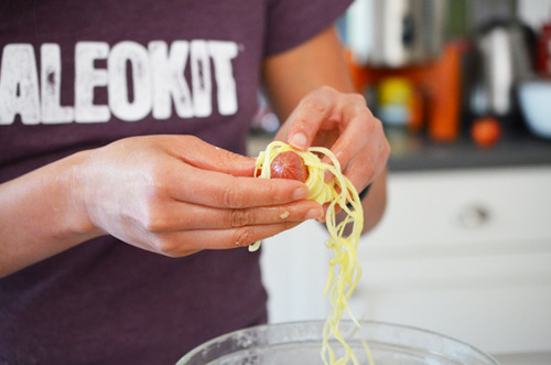 Wrapping spiralized sweet potatoes around healthy hotdogs to make Halloween Yummy Mummies