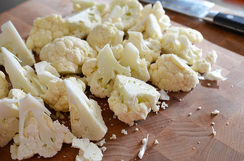 Cauliflower florets sitting on a cutting board.