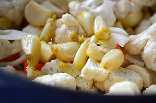 Roasted garlic cloves are added to a pot with the vegetables for Roasted Garlic Autumn Root Vegetable Mash.